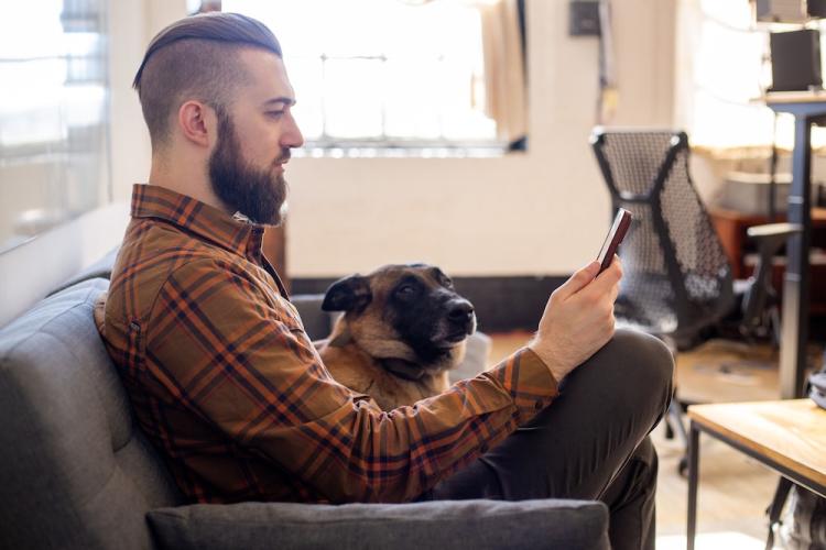 Mann mit einem SquareTrade-Gerät und einem Hund